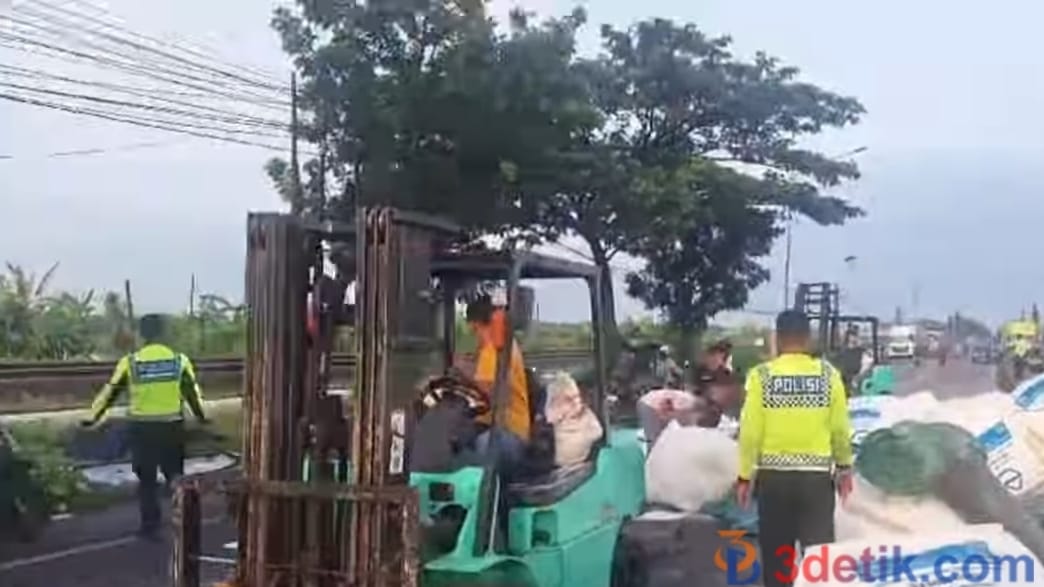 petugas Satlantas Polres Lamongan saat mengevakuasi truk trailer muatan gula pasir terguling di Jalan Lamongan Babat. [3detik.com]