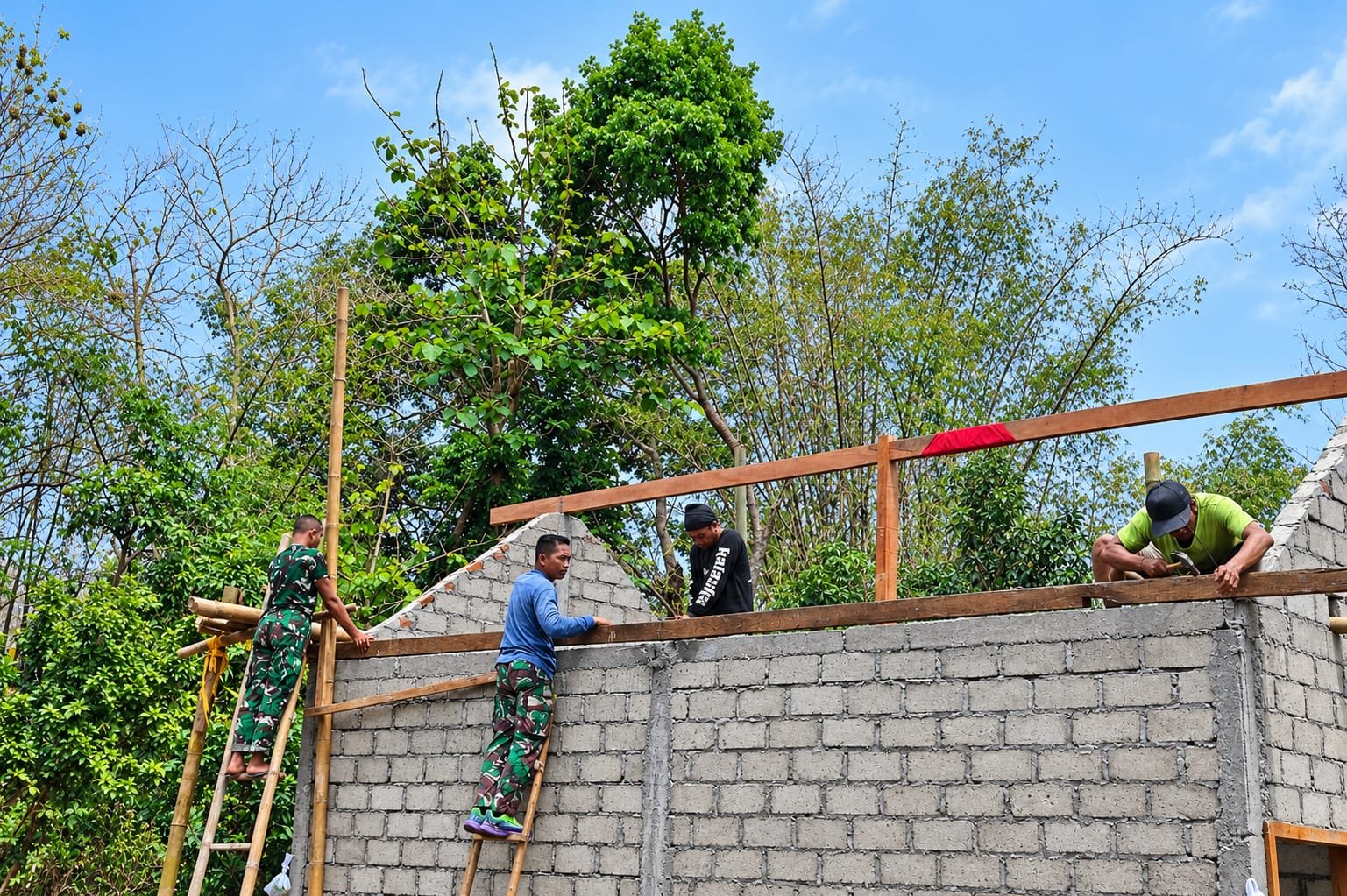 Satgas TMMD bersama warga bergotong royong memasang kuda-kuda sebagai rangka penopang atap rumah Mbah Waqilah